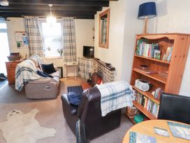 A living room with a sofa, armchair, and bookshelf at Merlin in Llithfaen near Nefyn