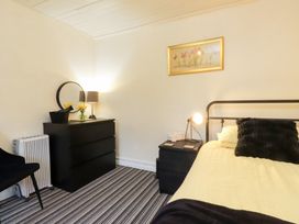 A bedroom with a bed, dresser, and lamp at Merlin in Llithfaen near Nefyn