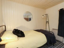A bedroom with a bed and mirror at Merlin in Llithfaen near Nefyn