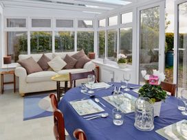 A conservatory with a dining table and a sofa at Sisial y Llyn in Bala