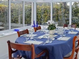 A dining table set with glasses and a plant in a conservatory at Sisial y Llyn in Bala