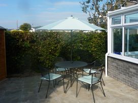 A patio with a table and chairs under an umbrella at Sisial y Llyn in Bala