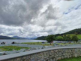 A lake with cars parked nearby at Sisial y Llyn in Bala