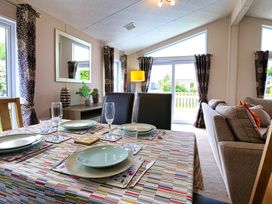 A dining room with a table set for meals and a sofa at Cheri in Southerness
