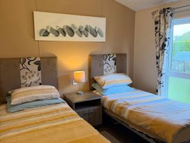 A bedroom with two beds and a nightstand at Cheri in Southerness