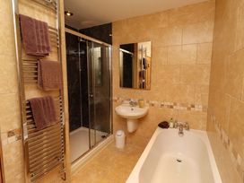 A bathroom with a bathtub, shower, sink, and towel rack at West Gate in Embleton