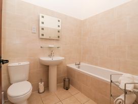 A bathroom with a sink, toilet, bathtub, and towels at Winsall Court I Gransmoor near Bridlington