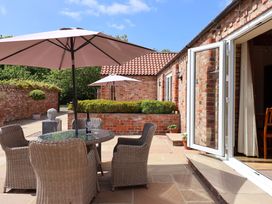 An outdoor area with a table and chairs under umbrellas at Winsall Court II in Gransmoor near Bridlington