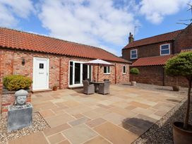 An outdoor seating area with an umbrella and flowerpots at Winsall Court II Gransmoor near Bridlington