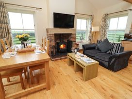 A living room with a fireplace and dining table at Bank Top Cottage in Embleton