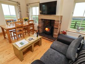 A living room with a fireplace and dining area at Bank Top Cottage in Embleton