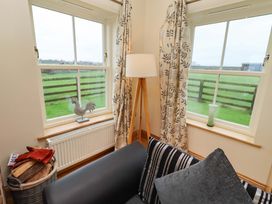 A sitting room with windows and a lamp at Bank Top Cottage in Embleton