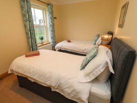 A bedroom with two beds and a window at Bank Top Cottage in Embleton