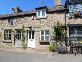 A stone building with flowers and a chair at Chancery Cottage in Hay-On-Wye