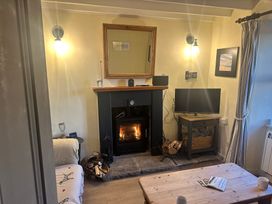 A living room with a fireplace and TV at 2 Sea View Cottage Nefyn