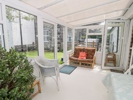 A conservatory with seating and plants at Dyffryn Bach in Glan-yr-afon near Corwen