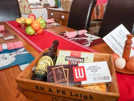 A dining table with fruit, biscuits, tea, and beer at Clara's Cottage in West Lutton near Malton
