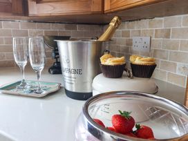 A kitchen with champagne, glasses, cupcakes, and strawberries at Clara's Cottage West Lutton near Malton