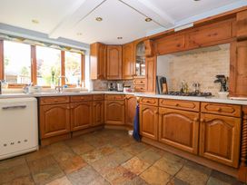 A kitchen with wooden cabinets and a stove at Clara's Cottage in West Lutton near Malton