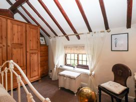 A bedroom with wooden furniture and a window at Clara's Cottage in West Lutton near Malton