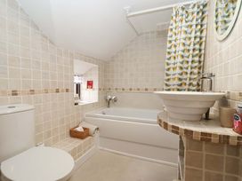 A bathroom with a toilet, bathtub, and sink at Clara's Cottage West Lutton near Malton