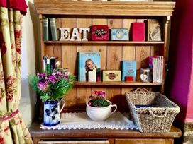 A shelf with books and a vase of flowers at Clara's Cottage West Lutton near Malton