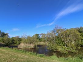 A landscape with water, grass, and trees at The Shippons in Abersoch