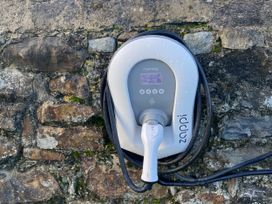 An electric vehicle charger mounted on a stone wall at Y Betws Abersoch