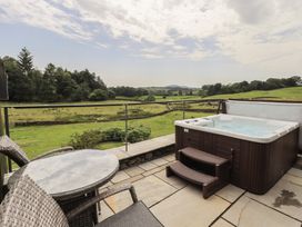 An outdoor area with a hot tub and seating at Acorn in Bowness-on-Windermere