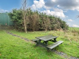 A picnic table on grass with bushes and a container in the background at Ash Lodge near Ulverston
