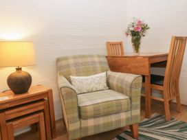 A snug area with an armchair and wooden table at Ash Lodge in Pennington near Ulverston