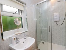 A bathroom with a sink, mirror, and shower at Ash Lodge in Pennington near Ulverston