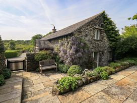 A stone cottage with a bench and garden at Pheasant Cottage in Beckside near Cartmel