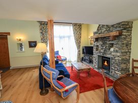 A living room with a stone fireplace and seating area at Pheasant Cottage Beckside near Cartmel