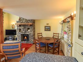 A living room with a fireplace and dining table at Pheasant Cottage Beckside near Cartmel