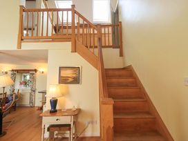 A staircase with wooden railing in a hallway at Pheasant Cottage near Cartmel
