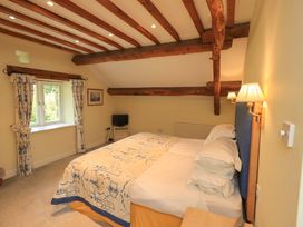 A bedroom with a bed and window at Pheasant Cottage in Beckside near Cartmel