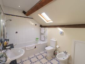 A bathroom with a bathtub, toilet, sink, and bidet at Pheasant Cottage in Beckside near Cartmel
