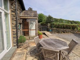 An outdoor seating area with a wooden table and chairs at Pheasant Cottage Beckside near Cartmel