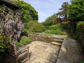 A garden with a stone pathway and a bench at Pheasant Cottage in Beckside near Cartmel