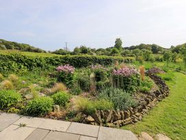 A garden with flowers and grass at Pheasant Cottage Beckside near Cartmel