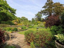 A garden with flowers and a bench at Pheasant Cottage in Beckside near Cartmel