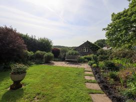 A garden with a bench and plants at Pheasant Cottage in Beckside near Cartmel