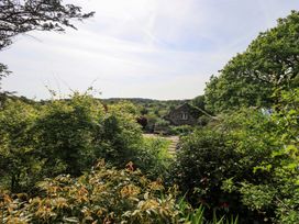 A garden view with a stone house and surrounding greenery at Pheasant Cottage near Cartmel
