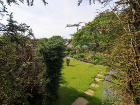 A garden with grass and a pathway at Pheasant Cottage Beckside near Cartmel