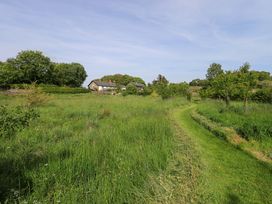 A grassy area with a pathway and trees at Pheasant Cottage in Beckside near Cartmel