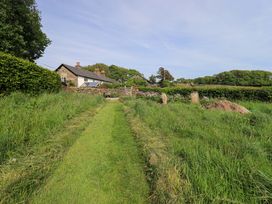 A house in a garden with a pathway at Pheasant Cottage Beckside near Cartmel