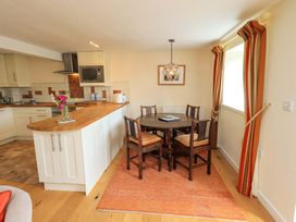 A kitchen with a dining area featuring a table and chairs at Kestrel Cottage Beckside near Cartmel