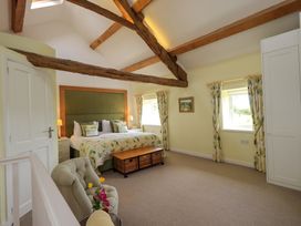 A bedroom with a bed and windows at Kestrel Cottage in Beckside near Cartmel