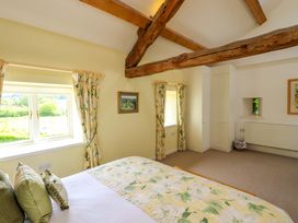A bedroom with windows and a bed at Kestrel Cottage Beckside near Cartmel